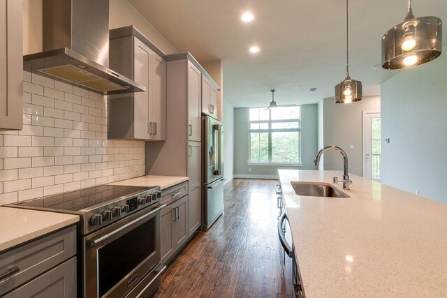 kitchen featuring sink, dark wood-type flooring, wall chimney range hood, light stone counters, and high quality appliances