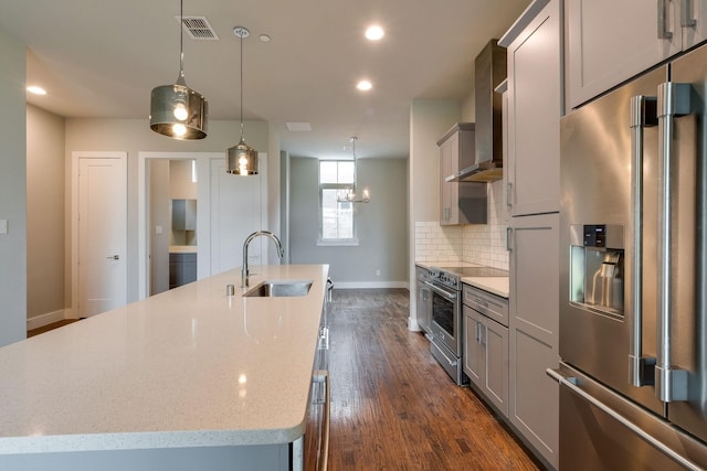 kitchen with sink, light stone counters, dark hardwood / wood-style flooring, an island with sink, and appliances with stainless steel finishes