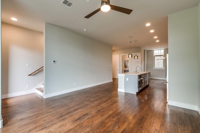 unfurnished living room with ceiling fan with notable chandelier, dark hardwood / wood-style flooring, and sink