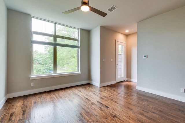 spare room featuring hardwood / wood-style floors, ceiling fan, and a healthy amount of sunlight