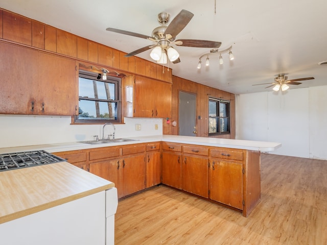 kitchen featuring kitchen peninsula, ceiling fan, sink, and light hardwood / wood-style floors