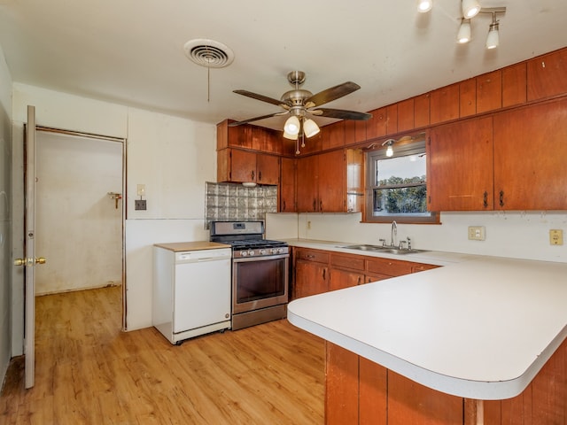 kitchen featuring ceiling fan, stainless steel gas stove, sink, kitchen peninsula, and light hardwood / wood-style floors