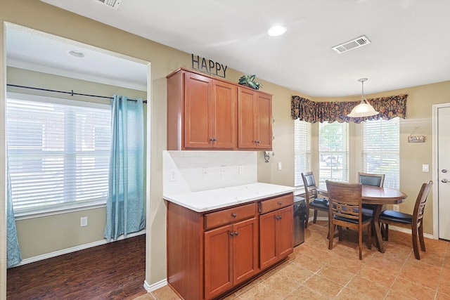 kitchen with backsplash, decorative light fixtures, light stone counters, and light hardwood / wood-style floors