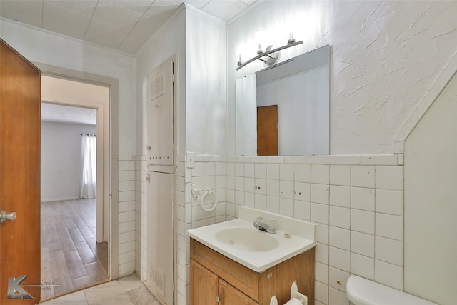 bathroom with hardwood / wood-style floors, vanity, toilet, and tile walls