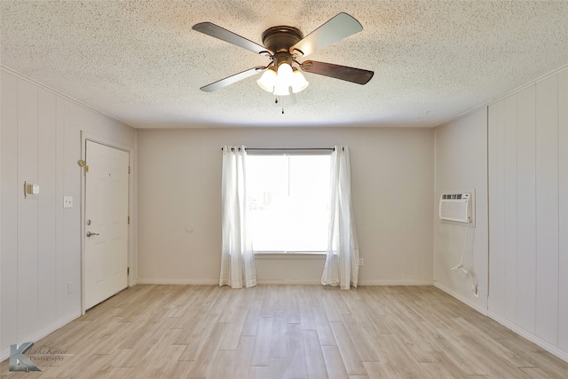 empty room featuring light wood-type flooring, a textured ceiling, and a wall unit AC