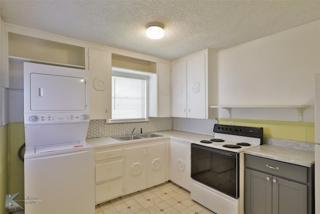 kitchen with electric stove, sink, gray cabinets, a textured ceiling, and stacked washer / drying machine