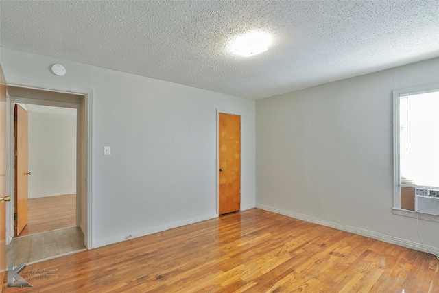 empty room with a textured ceiling and light wood-type flooring