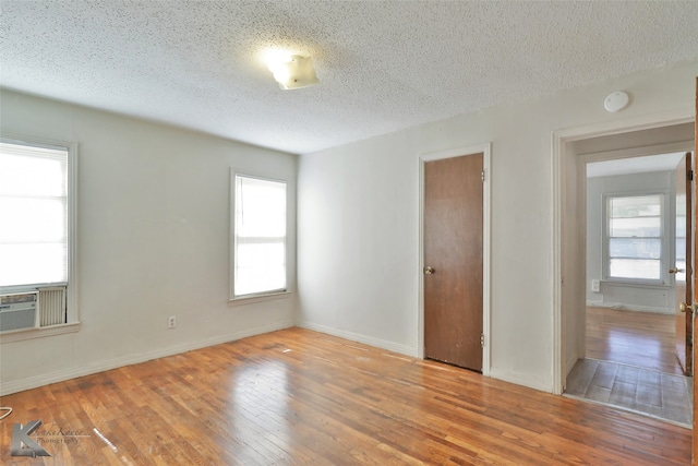 unfurnished room with a textured ceiling and light hardwood / wood-style flooring