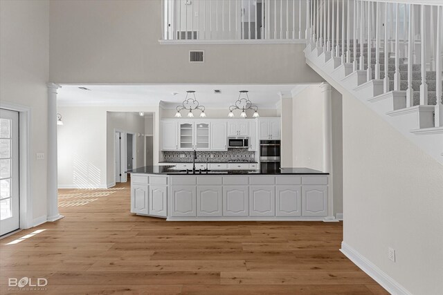 kitchen with white cabinetry, light hardwood / wood-style flooring, a notable chandelier, and appliances with stainless steel finishes