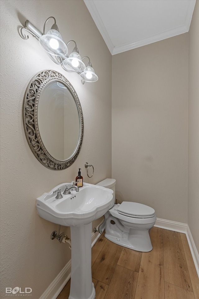 bathroom featuring crown molding, hardwood / wood-style floors, and toilet