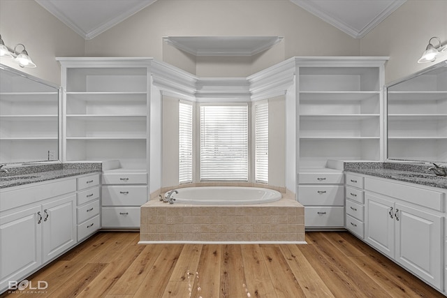 bathroom featuring wood-type flooring, lofted ceiling, a relaxing tiled tub, and ornamental molding