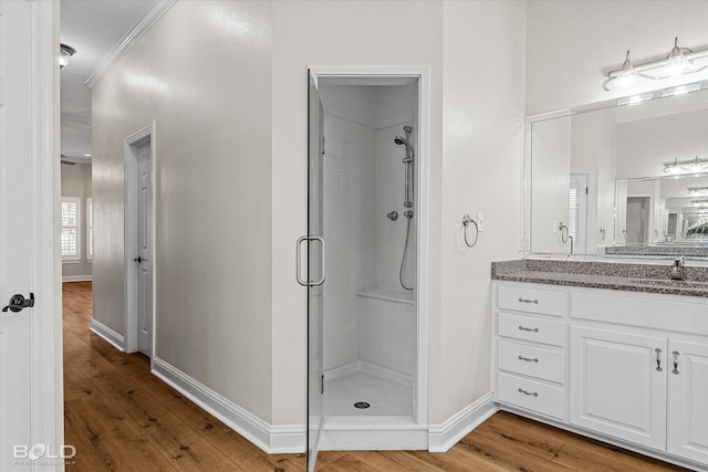 bathroom featuring wood-type flooring, vanity, ornamental molding, and a shower with shower door