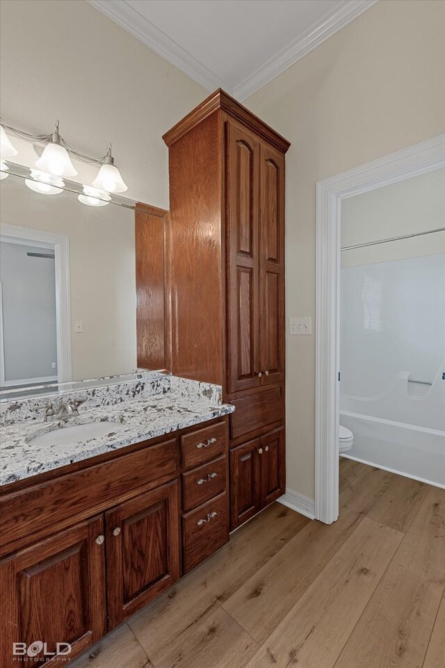 bathroom featuring hardwood / wood-style floors, vanity, toilet, and crown molding