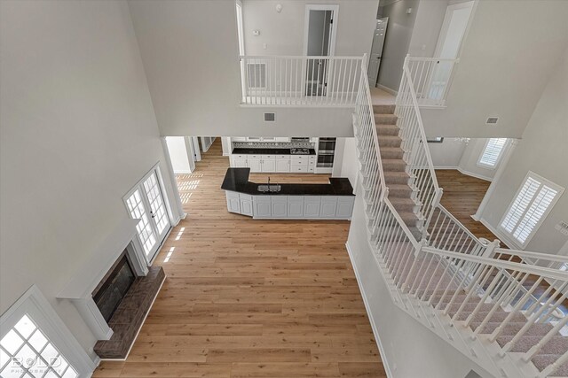 stairs featuring a high ceiling, french doors, and hardwood / wood-style floors