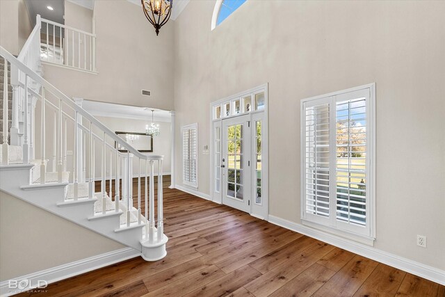 entryway featuring hardwood / wood-style floors, a notable chandelier, and a high ceiling