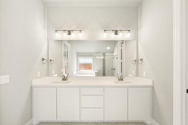 full bathroom featuring double vanity, a shower stall, baseboards, and a sink