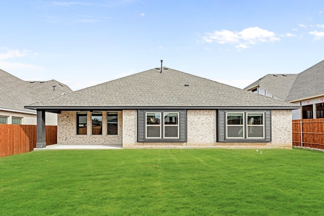 rear view of house featuring a fenced backyard, a shingled roof, a lawn, a patio area, and brick siding