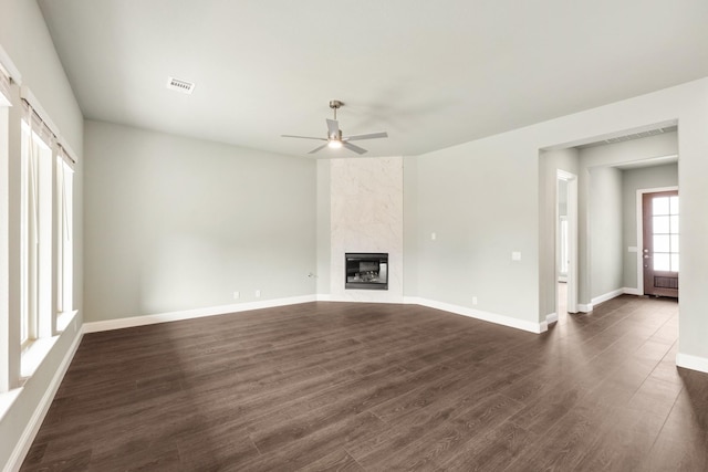 unfurnished living room with baseboards, visible vents, dark wood-style flooring, and a premium fireplace