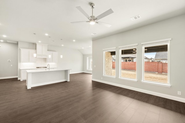 unfurnished living room featuring visible vents, baseboards, dark wood-type flooring, and a ceiling fan