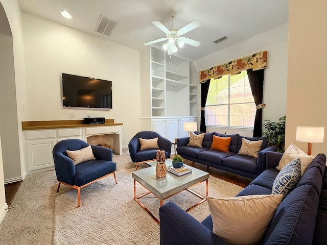 living room featuring built in shelves, ceiling fan, and hardwood / wood-style floors