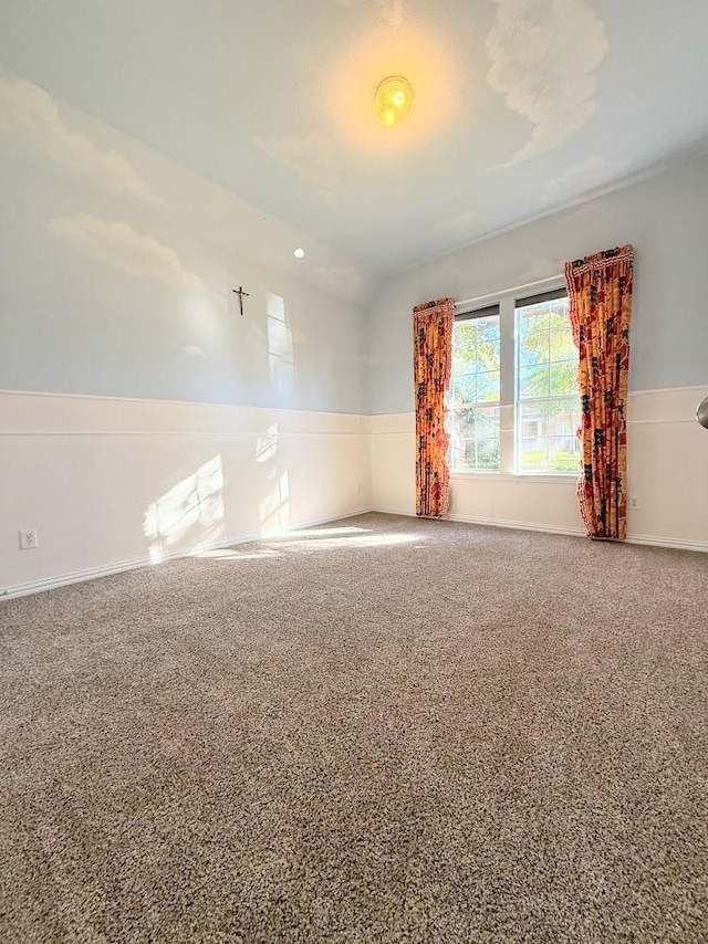 carpeted empty room featuring lofted ceiling