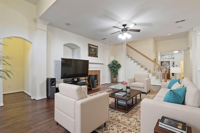 living room with decorative columns, a tiled fireplace, ceiling fan, and hardwood / wood-style floors