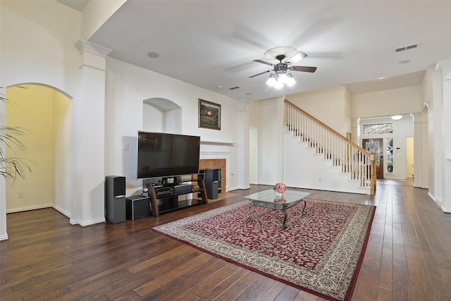 living room with ceiling fan, dark hardwood / wood-style flooring, ornate columns, and a tile fireplace