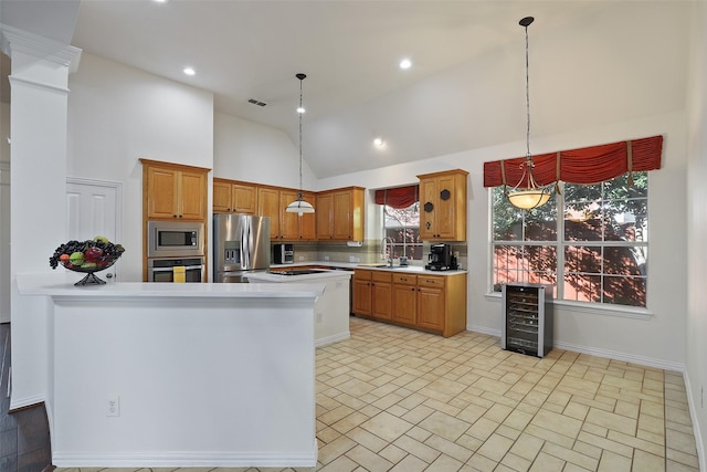 kitchen featuring pendant lighting, plenty of natural light, stainless steel appliances, and beverage cooler