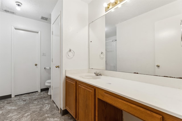 bathroom with vanity, a textured ceiling, and toilet