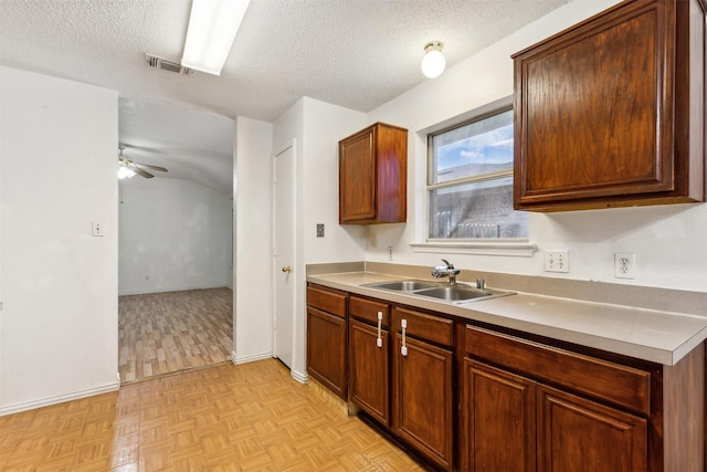 kitchen featuring light parquet floors, ceiling fan, sink, and a textured ceiling