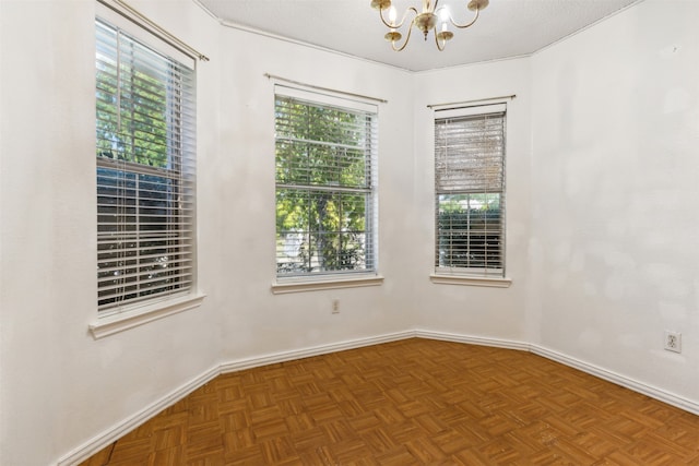 empty room featuring parquet floors, a textured ceiling, and a chandelier