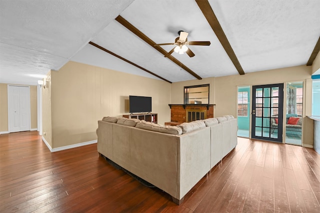 living room featuring lofted ceiling with beams, dark hardwood / wood-style floors, a textured ceiling, and ceiling fan