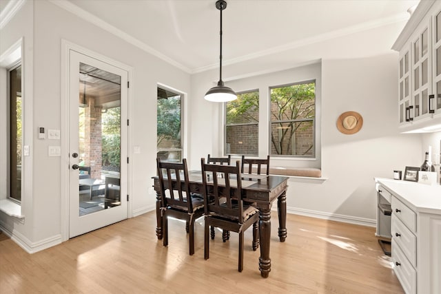 dining room with plenty of natural light, ornamental molding, and light wood-type flooring