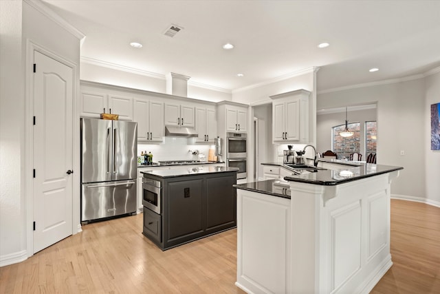 kitchen with sink, tasteful backsplash, a center island, light hardwood / wood-style flooring, and appliances with stainless steel finishes