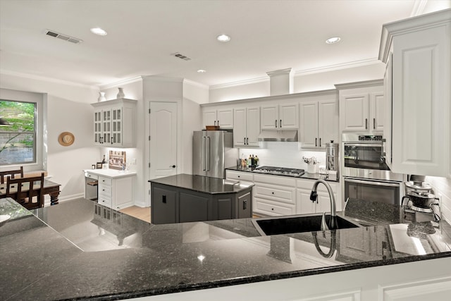 kitchen with sink, appliances with stainless steel finishes, a center island, kitchen peninsula, and dark stone counters