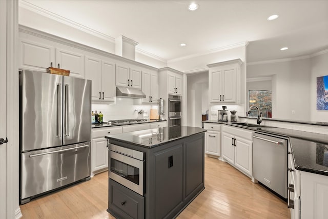 kitchen with sink, white cabinetry, dark stone countertops, stainless steel appliances, and a center island