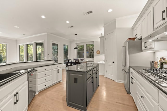 kitchen with white cabinets, dark stone counters, a center island, stainless steel appliances, and light hardwood / wood-style flooring