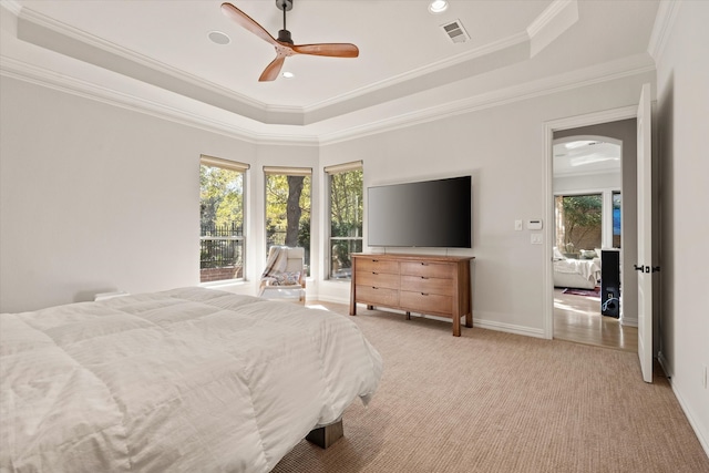 carpeted bedroom featuring a raised ceiling, ornamental molding, and ceiling fan