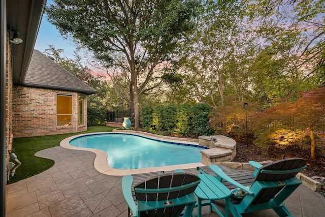 pool at dusk with a patio area