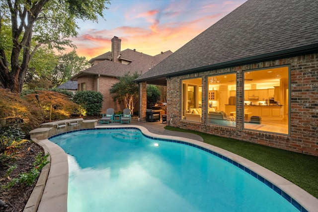 pool at dusk with a patio area