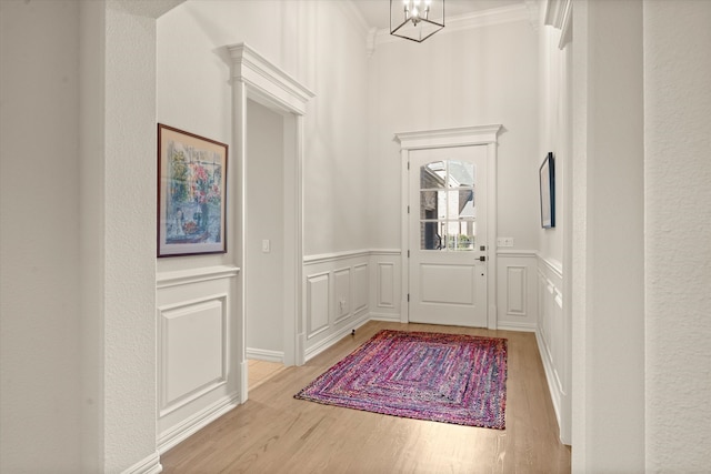 foyer entrance featuring crown molding, an inviting chandelier, and light hardwood / wood-style flooring