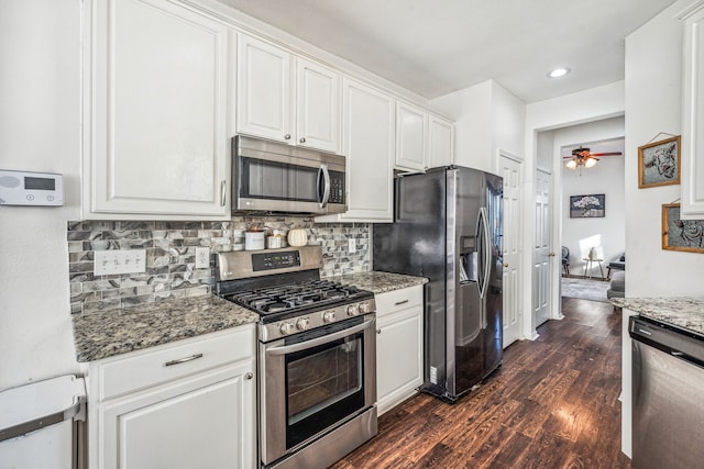 kitchen featuring white cabinets, appliances with stainless steel finishes, dark wood-type flooring, dark stone counters, and ceiling fan