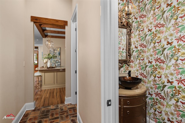 corridor featuring beam ceiling and sink