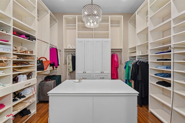 spacious closet with dark wood-type flooring and a chandelier