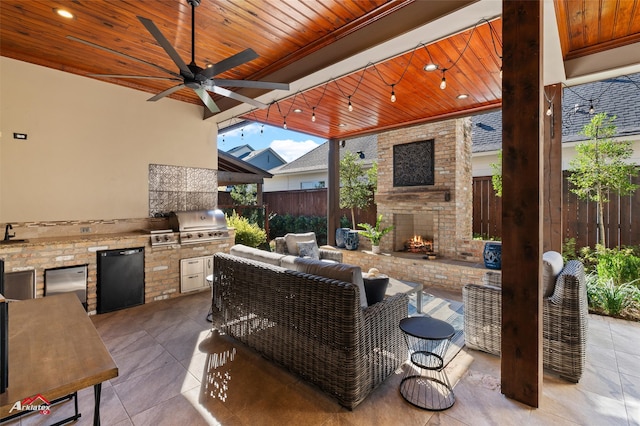 view of patio featuring ceiling fan, a grill, exterior fireplace, and an outdoor kitchen