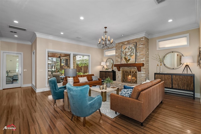 living room featuring a fireplace, wood-type flooring, ornamental molding, and a notable chandelier