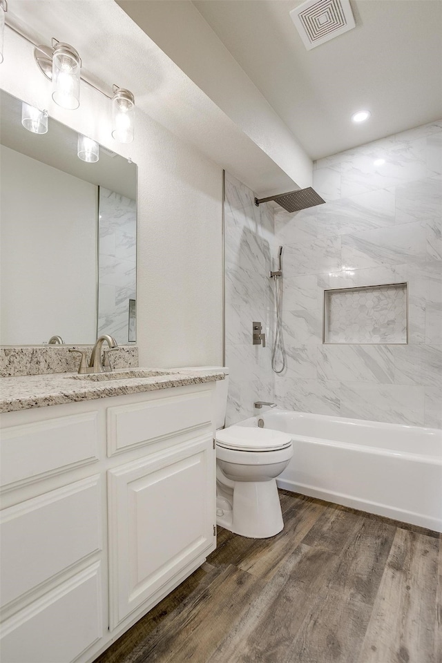 full bathroom featuring toilet, hardwood / wood-style floors, vanity, and tiled shower / bath