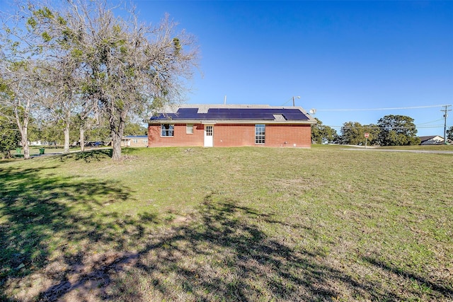 back of property featuring a yard and solar panels