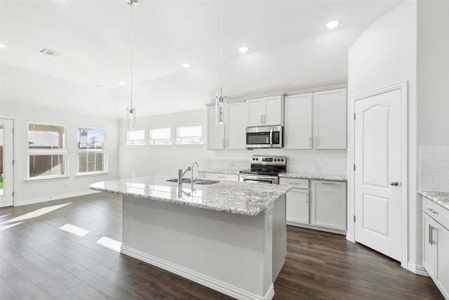 kitchen featuring dark hardwood / wood-style flooring, stainless steel appliances, hanging light fixtures, and a center island with sink