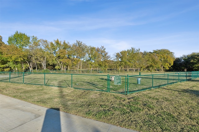 view of tennis court with a lawn and a rural view